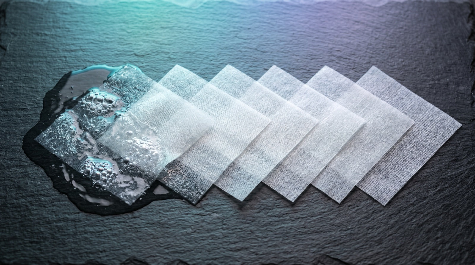 Laundry detergent sheets dissolving on dark slate with teal-blue light — best detergent sheets 2026