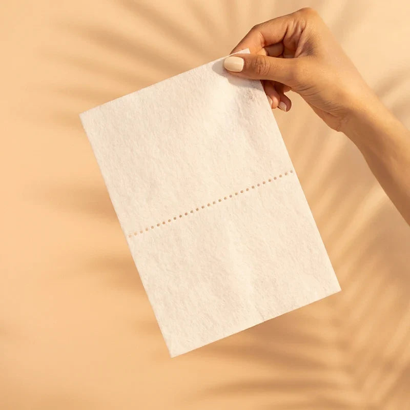 Single QLEAN Sweet Summer Love laundry detergent sheet held in hand against cream peach background