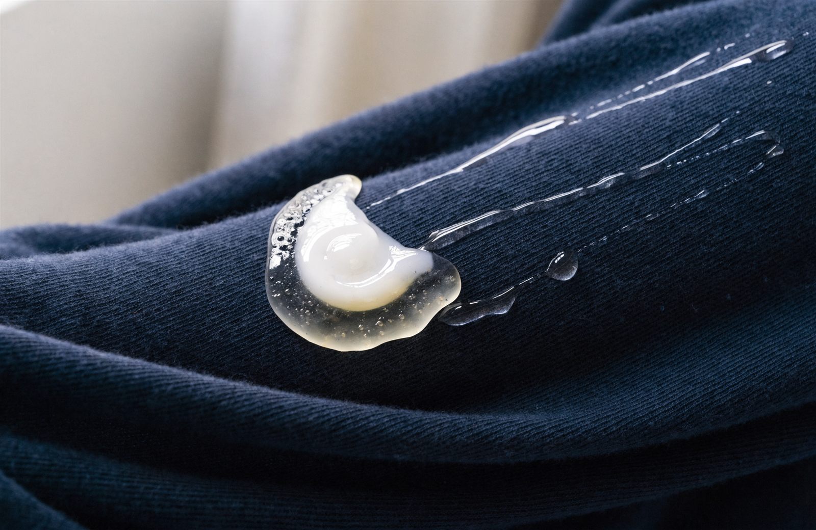 A half-dissolved laundry pod leaving sticky residue on a dark sweater sleeve