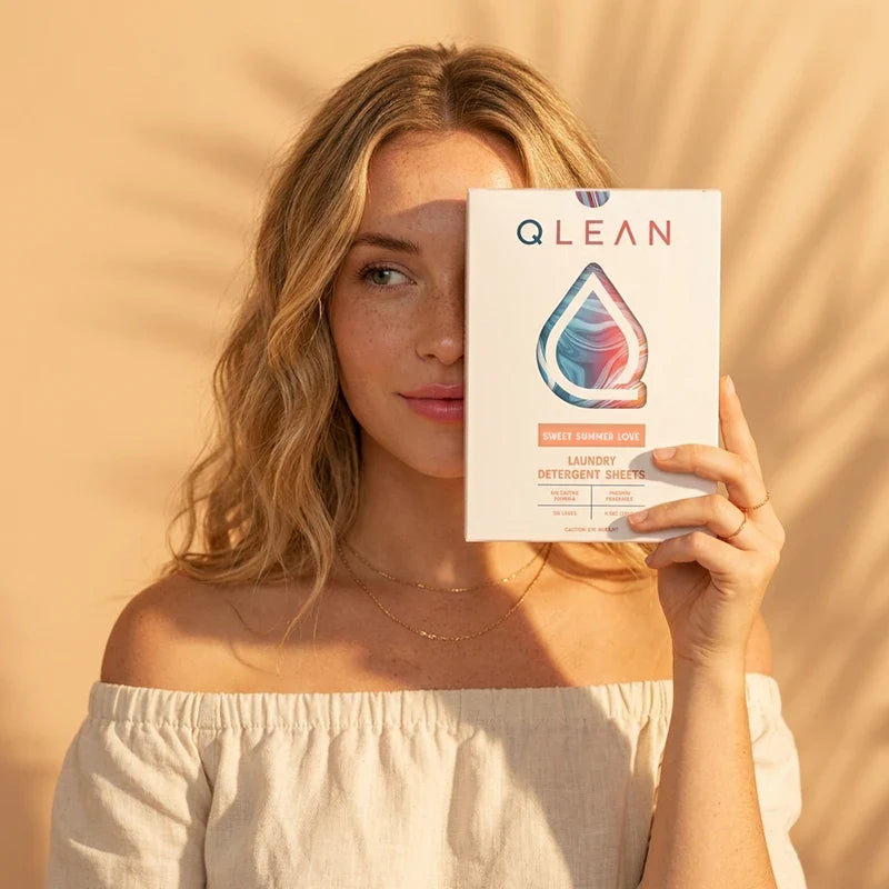 Model holding QLEAN Sweet Summer Love laundry detergent sheets box outdoor summer lifestyle scene