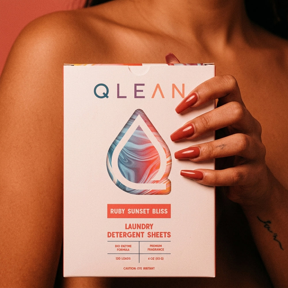 A hand holding the Qlean Ruby Sunset Bliss 120-load detergent sheet pack